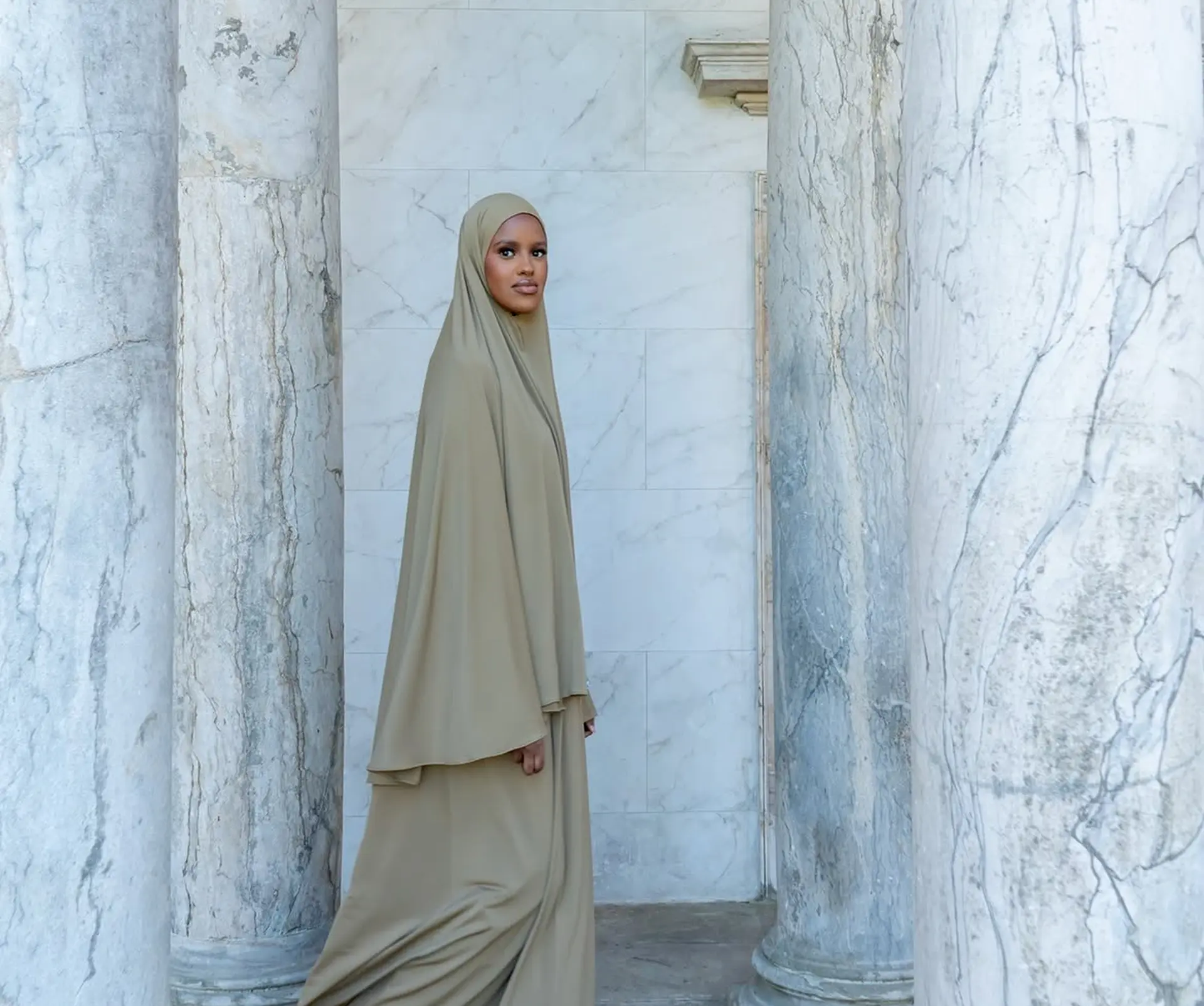 Model i beige khimar sæt mellem marmorsøjler